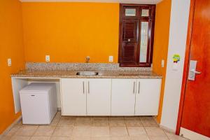 a kitchen with a sink and an orange wall at Garbos Soleil Hotel in Natal