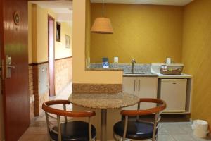 a kitchen with a counter with two stools and a sink at Garbos Soleil Hotel in Natal +55 photos