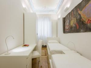 フィレンツェにあるApartments Florence - Duomo Artのベッド2台が備わる客室で、壁には絵画が飾られています。