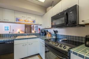 a kitchen with white cabinets and black appliances at Ocean Song - 2 Bedroom Oceanfront Penthouse Condo in Kill Devil Hills, Spacious Layout in Kill Devil Hills +32 photos