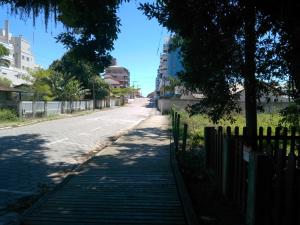 una calle vacía con una valla y un árbol en Chalés no centro de Bombinhas, en Bombinhas