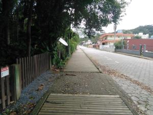 una calle vacía con una valla de madera y una acera en Chalés no centro de Bombinhas, en Bombinhas