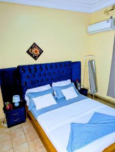 a large bed with a blue headboard in a bedroom at Appartement Meublé 3 Chambres in Douala