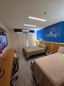 a hotel room with two beds and a flat screen tv at Flat 811 - Hotel Comfort Taguatinga in Brasília