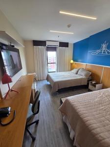 a hotel room with two beds and a desk at Flat 811 - Hotel Comfort Taguatinga in Brasília