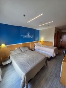 a hotel room with two beds and a blue wall at Flat 811 - Hotel Comfort Taguatinga in Brasília