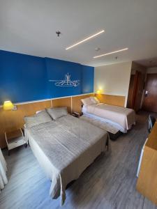 a hotel room with two beds and a blue wall at Flat 811 - Hotel Comfort Taguatinga in Brasília