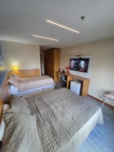 a hotel room with two beds and a flat screen tv at Flat 811 - Hotel Comfort Taguatinga in Brasília +14 photos