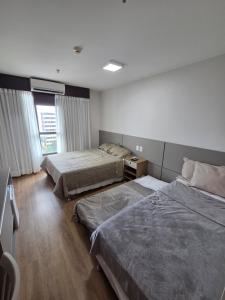 a bedroom with two beds and a desk and window at Flat 709 - Hotel Comfort Taguatinga in Brasília