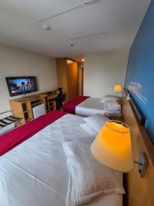 a hotel room with two beds and a television at Flat 1015 - Hotel Comfort Taguatinga in Brasília
