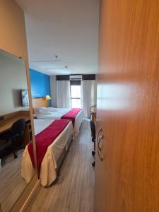 a hotel room with two beds and a desk at Flat 1015 - Hotel Comfort Taguatinga in Brasília