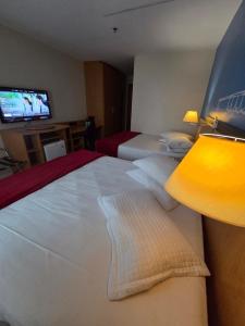 a hotel room with two beds and a flat screen tv at Flat 1015 - Hotel Comfort Taguatinga in Brasília