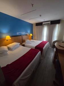 a hotel room with two beds and a blue wall at Flat 1015 - Hotel Comfort Taguatinga in Brasília +35 photos
