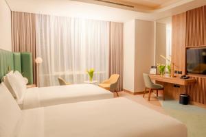 a hotel room with two beds and a desk at Edge Riyadh Al Rabie in Riyadh