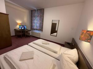 a hotel room with two beds and a desk at Hotel Merkur in Zwickau