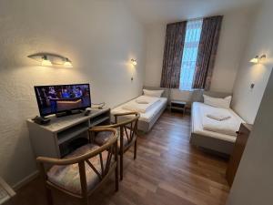 a room with two beds and a flat screen tv at Hotel Merkur in Zwickau +21 photos