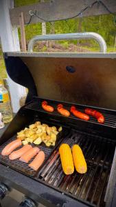 a grill with hot dogs and corn on the grill at Summer cottage Taipalsaari in Vehkataipale