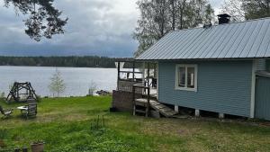 a blue house sitting next to a body of water at Summer cottage Taipalsaari in Vehkataipale