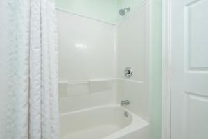 eine weiße Badewanne mit Duschvorhang im Badezimmer in der Unterkunft Drifting Sands Oceanfront Hotel in Ship Bottom