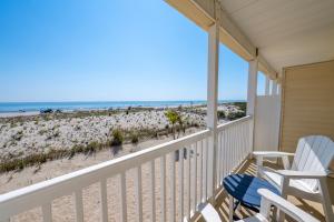 eine Veranda mit zwei Stühlen und der Strand in der Unterkunft Drifting Sands Oceanfront Hotel in Ship Bottom + 88 Fotos