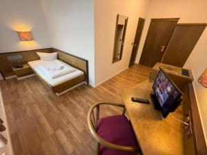 a room with a bed and a desk with a television at Hotel Merkur in Zwickau