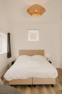 a bedroom with a white bed and a chandelier at De Vlaeke in Kerkwerve +11 photos