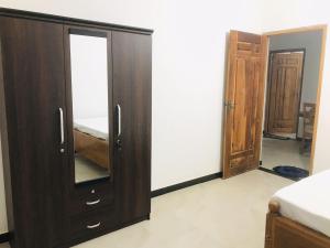 a bedroom with a wooden cabinet and a mirror at Blue Deer Villa in Trincomalee