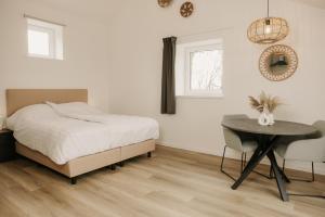 a bedroom with a bed and a table and a window at De Vlaeke in Kerkwerve