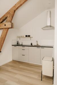 a kitchen with white cabinets and a wooden floor at De Vlaeke in Kerkwerve