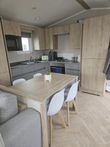 a kitchen with a wooden table and white chairs at Crozzer's Place in Heysham