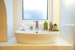 a white sink in a bathroom with a window at Golf Links Cottage - Views of Royal County Down Golf Course in Newcastle
