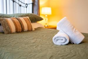 a bed with two rolled towels on top of it at Golf Links Cottage - Views of Royal County Down Golf Course in Newcastle +40 photos