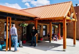 two men standing outside of a building with a roof at Pintler's Portal Hostel in Anaconda