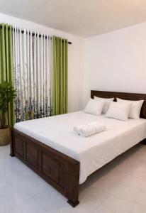 a bedroom with a large bed with green curtains at Jasmine Breeze Villa in Kadawata