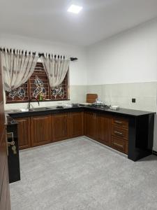 a large kitchen with wooden cabinets and a window at Jasmine Breeze Villa in Kadawata