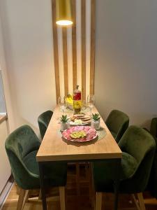 a table with a plate of food on it with green chairs at Emerald Mamba - Titova Vila in Zlatibor