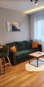 a living room with a green couch and a table at Emerald Mamba - Titova Vila in Zlatibor