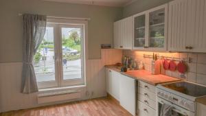 a kitchen with white cabinets and a large window at Svingen Apartments in Balestrand +16 photos