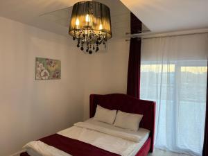 a bedroom with a bed with a chandelier and a window at VISAJ Jacuzzi Romantic in Timişoara