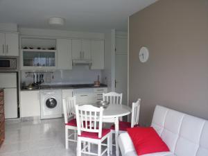 cocina con mesa y sillas blancas y sofá blanco en Apartamento Portosín, en Portosín