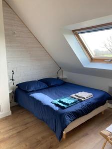 a bedroom with a bed with blue sheets and a window at Portec la mer et le sentier côtier à pied in Moëlan-sur-Mer