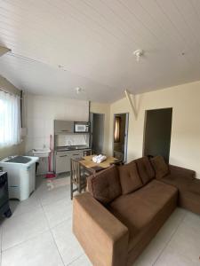 a living room with a brown couch and a kitchen at Casa São Francisco do Sul - #2 in São Francisco do Sul