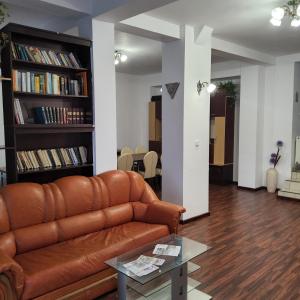 a living room with a brown leather couch and bookshelves at Conacul de la Dunăre, Eșelnița in Eşelniţa