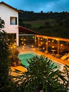a house with a swimming pool in front of it at Pousada DrChico in Poço Fundo