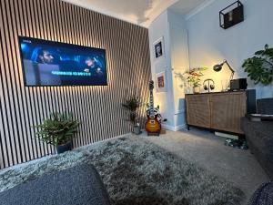 a living room with a flat screen tv on a striped wall at Bungalow 44 - The Norfolk Broads At Your Door in Lowestoft