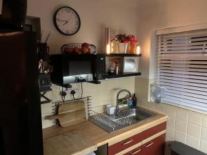 a kitchen with a sink and a clock on the wall at Bungalow 44 - The Norfolk Broads At Your Door in Lowestoft