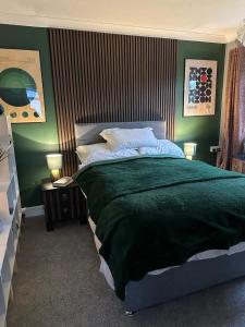 a bedroom with a large bed with green walls at Bungalow 44 - The Norfolk Broads At Your Door in Lowestoft +19 photos