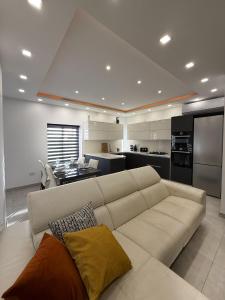 a living room with a white couch and a kitchen at Bright Modern Apartment with Rooftop in Mqabba