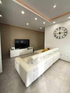 a living room with a large white couch and a clock at Bright Modern Apartment with Rooftop in Mqabba