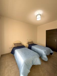 two beds sitting next to each other in a bedroom at Bright Modern Apartment with Rooftop in Mqabba